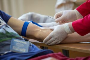 Healthcare professional drawing blood from a patient in a medical setting.